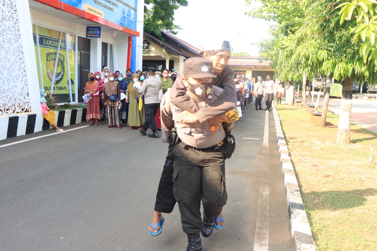 Salut, Anggota Polisi Ini Gendong Warga Saat Penyaluran Bantuan Tunai
